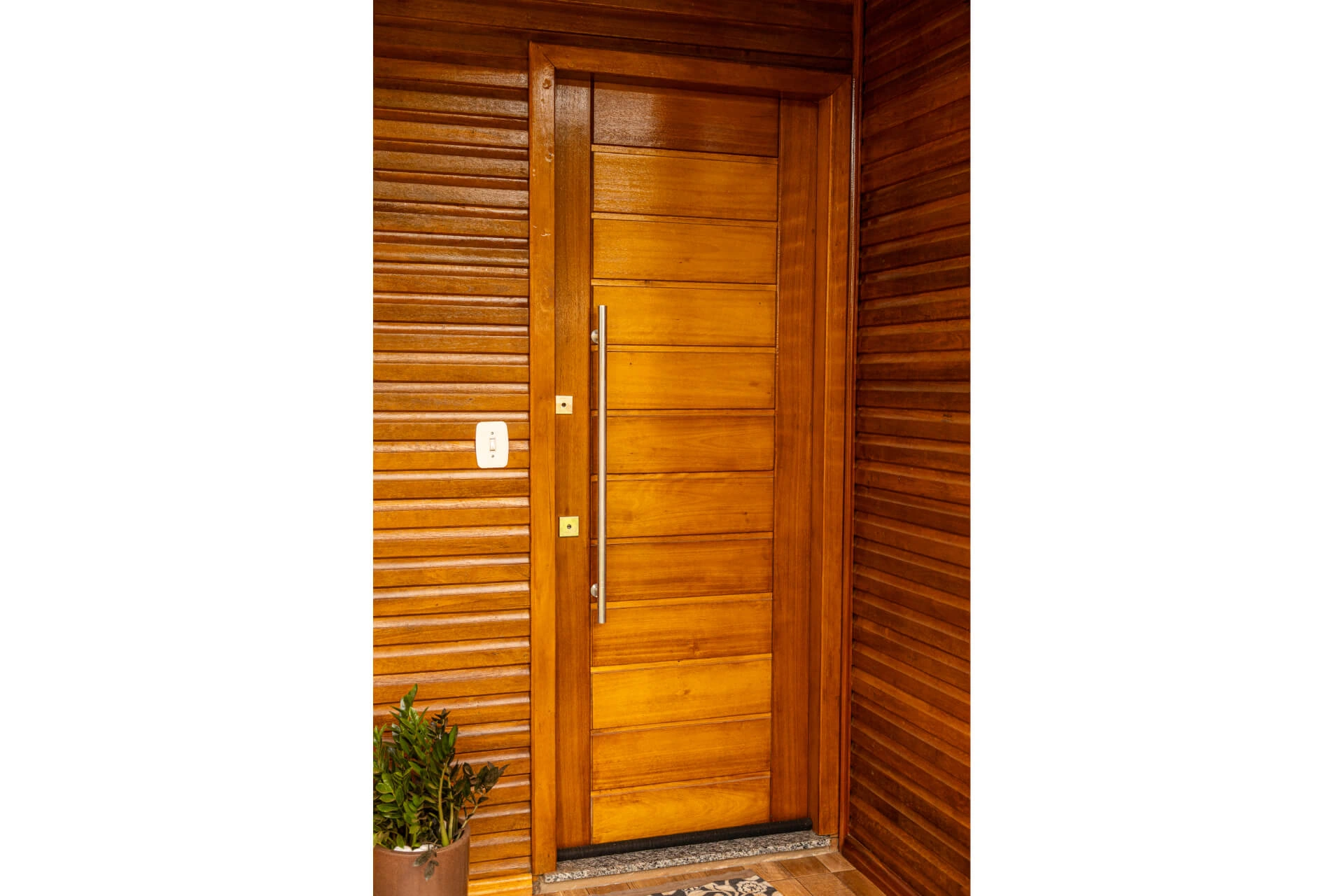 Porta externa em madeira maciça instalada na entrada de uma residência